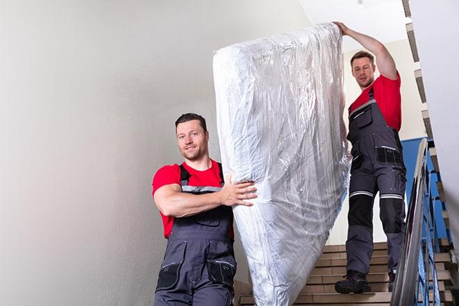 two workers hauling a box spring out of a building in Campo CA